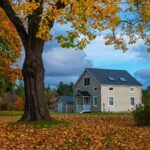 A charming countryside home surrounded by vibrant fall foliage, representing the peaceful allure of hidden US destinations perfect for a scenic and quiet escape.